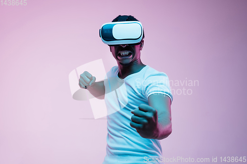 Image of Young african-american man\'s using VR-glasses in neon light
