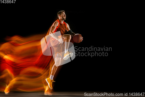 Image of Young caucasian basketball player against dark background in mixed light
