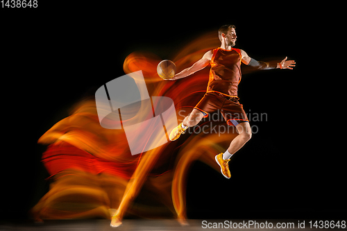 Image of Young caucasian basketball player against dark background in mixed light