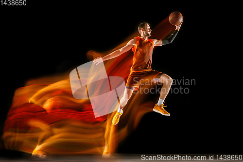 Image of Young caucasian basketball player against dark background in mixed light