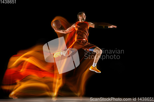 Image of Young caucasian basketball player against dark background in mixed light