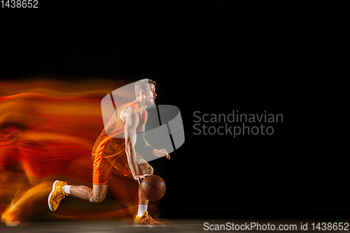 Image of Young caucasian basketball player against dark background in mixed light