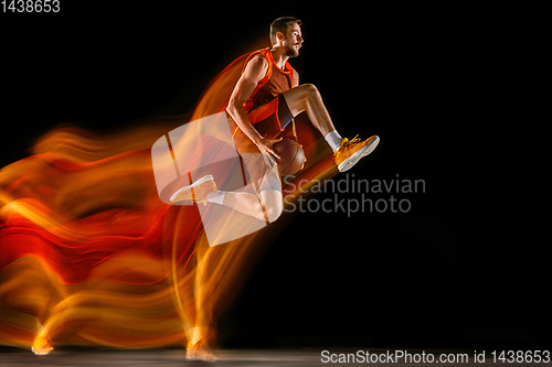 Image of Young caucasian basketball player against dark background in mixed light