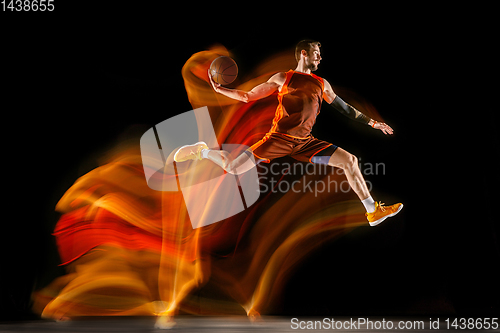 Image of Young caucasian basketball player against dark background in mixed light