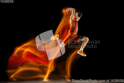 Image of Young caucasian basketball player against dark background in mixed light