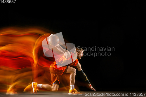 Image of Young caucasian basketball player against dark background in mixed light