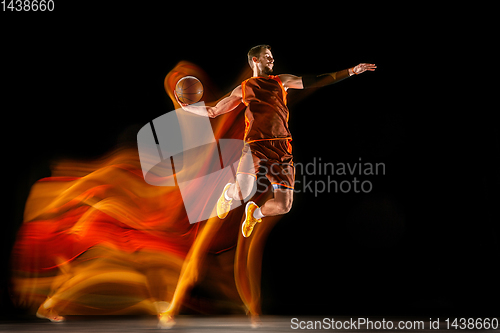 Image of Young caucasian basketball player against dark background in mixed light