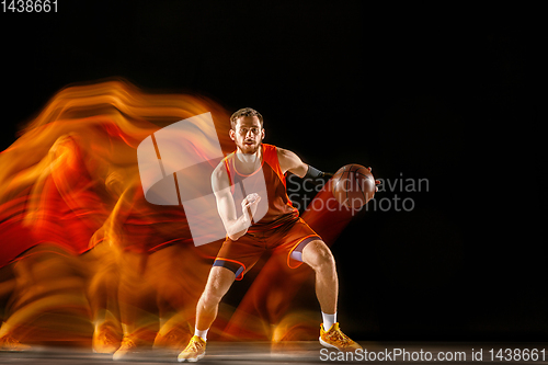 Image of Young caucasian basketball player against dark background in mixed light