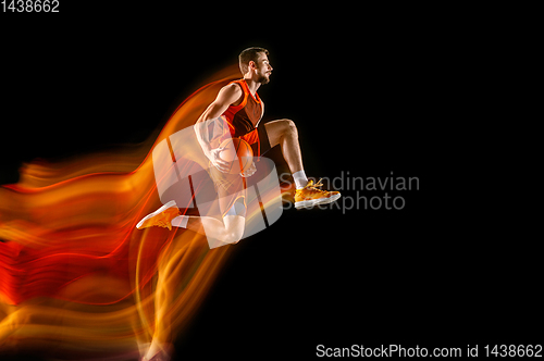 Image of Young caucasian basketball player against dark background in mixed light