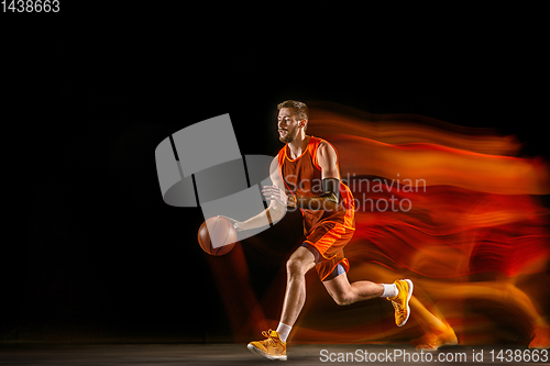 Image of Young caucasian basketball player against dark background in mixed light