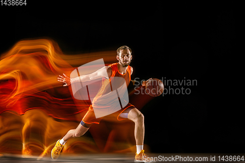 Image of Young caucasian basketball player against dark background in mixed light