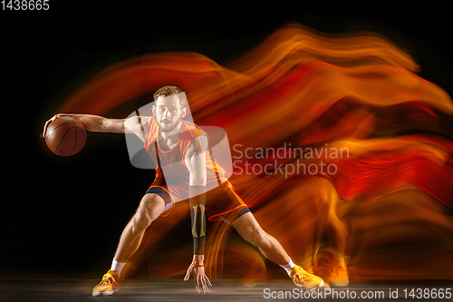 Image of Young caucasian basketball player against dark background in mixed light