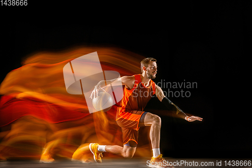 Image of Young caucasian basketball player against dark background in mixed light