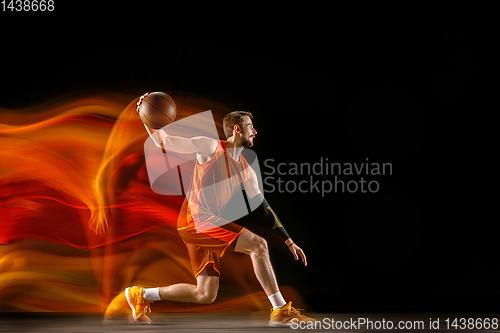 Image of Young caucasian basketball player against dark background in mixed light