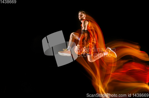 Image of Young caucasian basketball player against dark background in mixed light