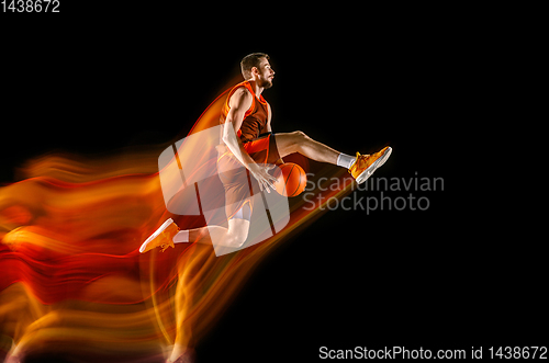 Image of Young caucasian basketball player against dark background in mixed light