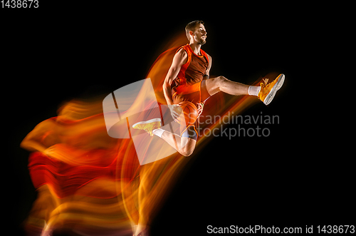 Image of Young caucasian basketball player against dark background in mixed light