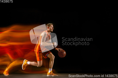 Image of Young caucasian basketball player against dark background in mixed light