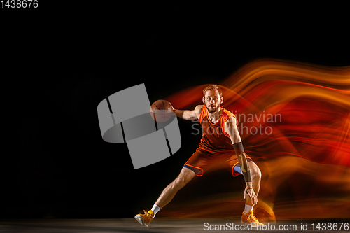 Image of Young caucasian basketball player against dark background in mixed light