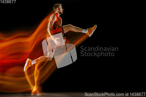 Image of Young caucasian basketball player against dark background in mixed light