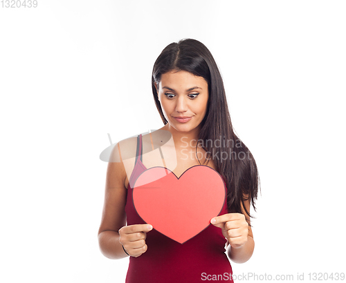 Image of beautiful happy brunette woman holding and showing a big red hea