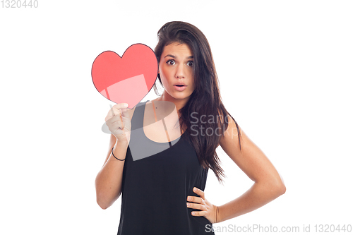 Image of beautiful happy brunette woman holding and showing a big red hea