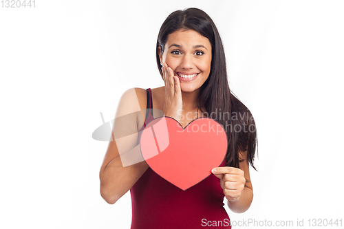 Image of beautiful happy brunette woman holding and showing a big red hea