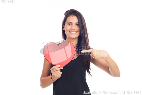 Image of beautiful happy brunette woman holding and showing a big red hea