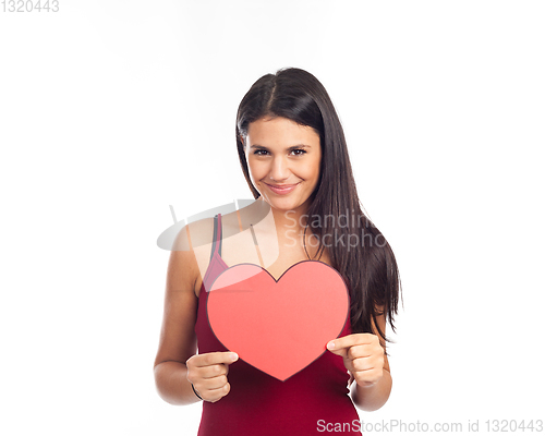 Image of beautiful happy brunette woman holding and showing a big red hea