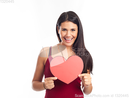 Image of beautiful happy brunette woman holding and showing a big red hea