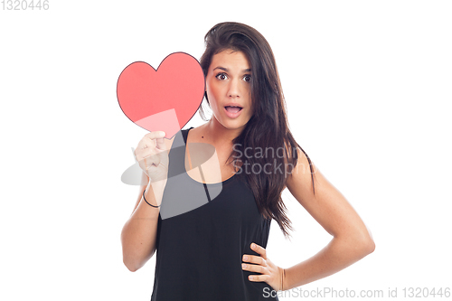 Image of beautiful happy brunette woman holding and showing a big red hea