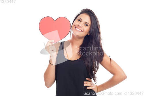 Image of beautiful happy brunette woman holding and showing a big red hea