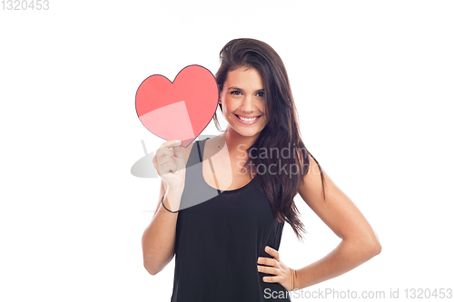 Image of beautiful happy brunette woman holding and showing a big red hea