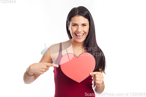Image of beautiful happy brunette woman holding and showing a big red hea