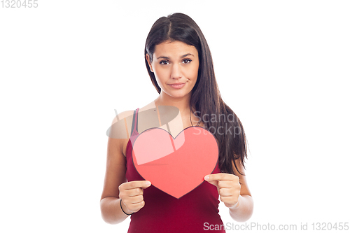 Image of beautiful happy brunette woman holding and showing a big red hea