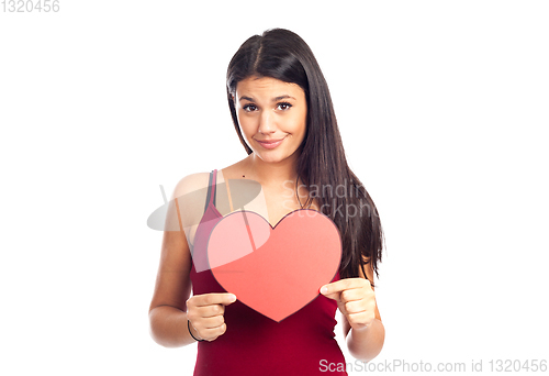 Image of beautiful happy brunette woman holding and showing a big red hea