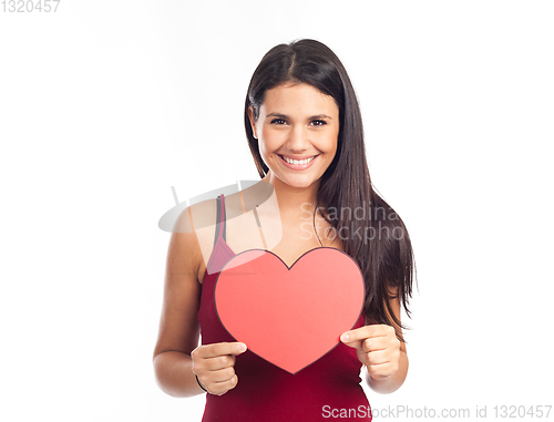 Image of beautiful happy brunette woman holding and showing a big red hea