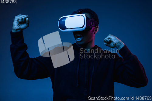 Image of Young african-american man\'s using VR-glasses in neon light