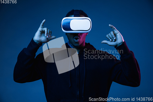 Image of Young african-american man\'s using VR-glasses in neon light