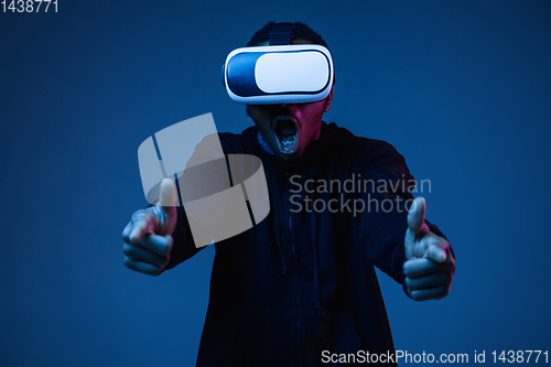 Image of Young african-american man\'s using VR-glasses in neon light