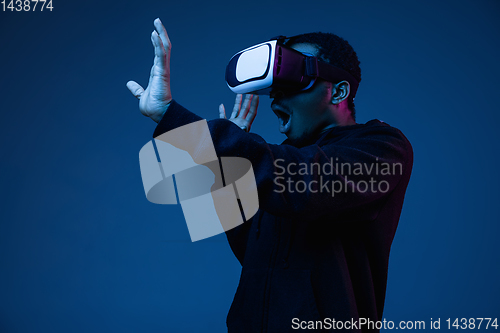 Image of Young african-american man\'s using VR-glasses in neon light