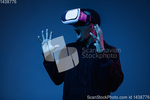 Image of Young african-american man\'s using VR-glasses in neon light