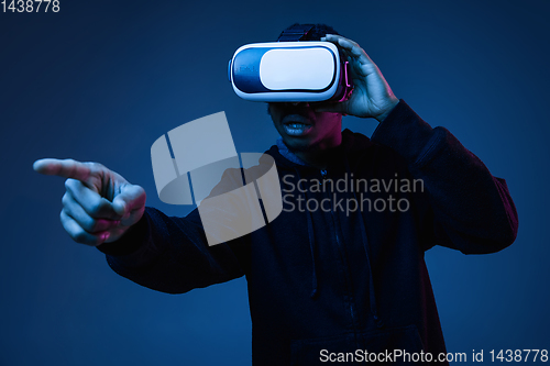 Image of Young african-american man\'s using VR-glasses in neon light
