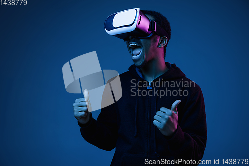 Image of Young african-american man\'s using VR-glasses in neon light