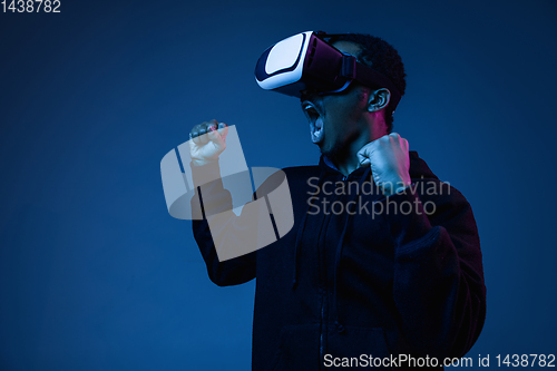 Image of Young african-american man\'s using VR-glasses in neon light