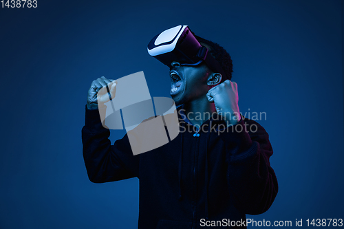 Image of Young african-american man\'s using VR-glasses in neon light