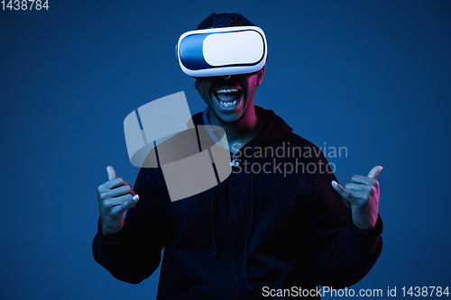 Image of Young african-american man\'s using VR-glasses in neon light