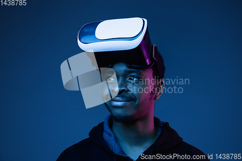 Image of Young african-american man\'s using VR-glasses in neon light