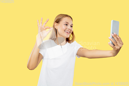 Image of Caucasian young woman\'s half-length portrait on yellow background