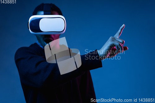 Image of Young african-american man\'s using VR-glasses in neon light